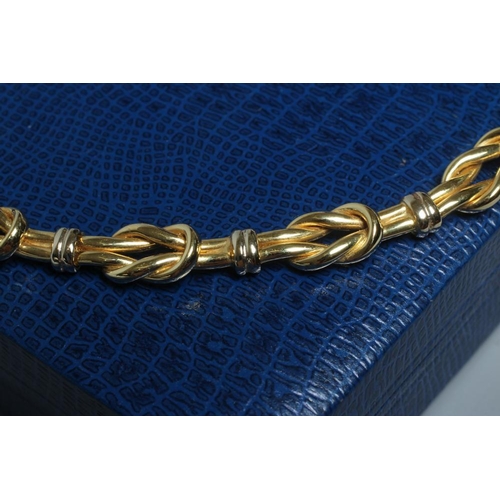 257 - A ROBERT COIN TWO TONE REEF KNOT CHOKER with slide clasp and safety clip, stamped 750, 1226VI, 46.7g... 