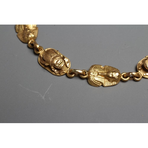 279 - AN EGYPTIANESQUE BRACELET, stamped 750, with scarab and face mask cast links and spring ring fastene... 