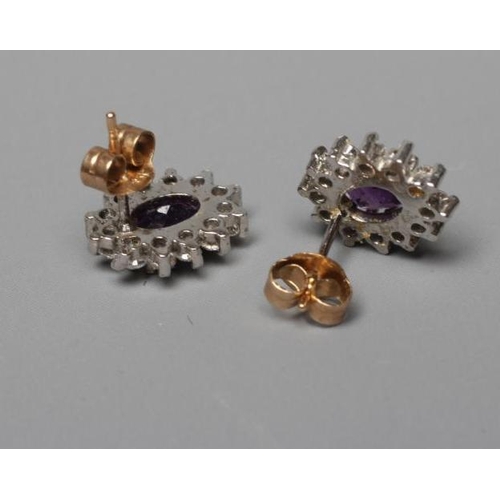 366 - A PAIR OF AMETHYST AND DIAMOND CLUSTER EAR STUDS, the oval facet cut amethysts claw set to a border ... 