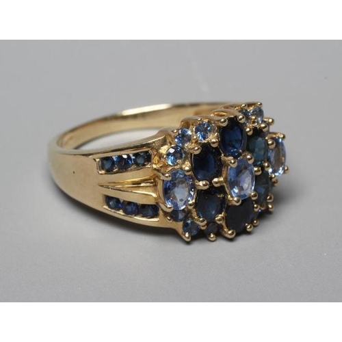 369 - A TANZANITE AND SAPPHIRE CLUSTER RING, the three oval facet cut tanzanites claw set to a border of s... 