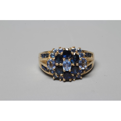 369 - A TANZANITE AND SAPPHIRE CLUSTER RING, the three oval facet cut tanzanites claw set to a border of s... 