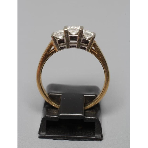 374 - A THREE STONE DIAMOND RING, the Princess cut stones bar set to a plain shank, stamped 18K CORONA, 75... 