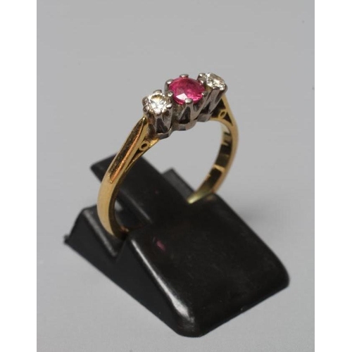 389 - A THREE STONE RUBY AND DIAMOND RING, the central facet cut ruby claw set and flanked by two small br... 