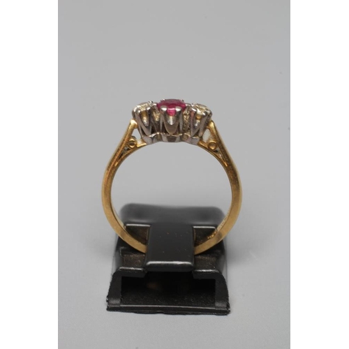 389 - A THREE STONE RUBY AND DIAMOND RING, the central facet cut ruby claw set and flanked by two small br... 