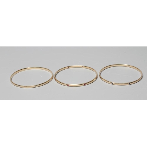 408 - A MATCHED SET OF THREE STONE SET 9CT GOLD BANGLES, set with either eight diamonds, rubies or sapphir... 