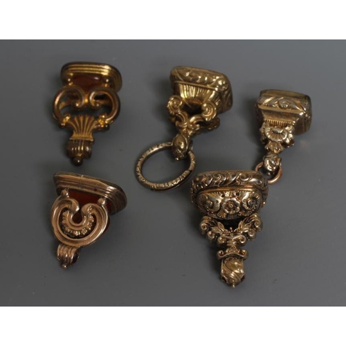 96 - FIVE GEORGIAN AND LATER GILT METAL FOB SEALS, four set with cornelian (one engraved with a lion ramp... 