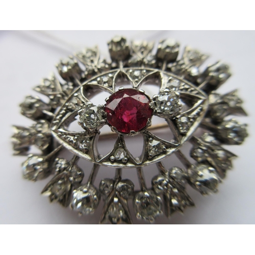 396 - A RUBY AND DIAMOND BROOCH, the central circular facet cut ruby claw set to open borders of old mix c... 