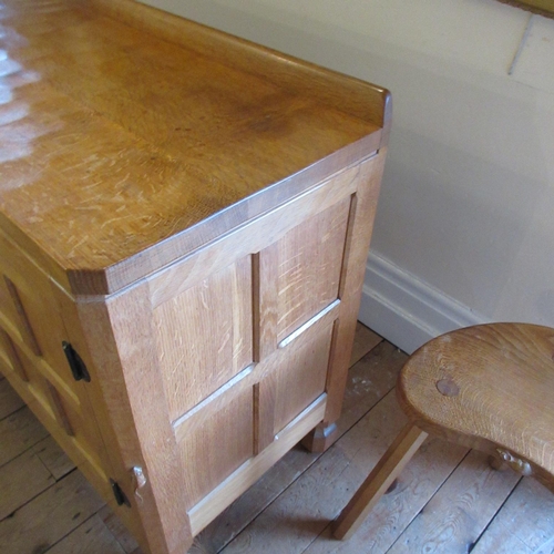 655 - A ROBERT THOMPSON ADZED OAK SIDEBOARD of canted oblong form with ledge back, moulded edged top, thre... 