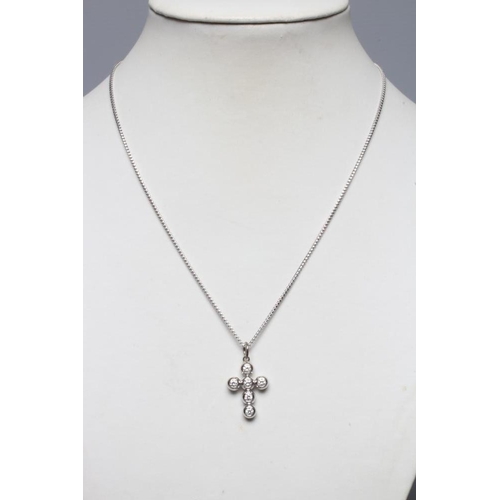 212 - A SIX STONE DIAMOND CROSS PENDANT, the round brilliants collet set in rub-over settings in white met... 