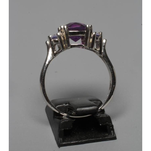 225 - AN AMETHYST RING, the rose cut cushion stone claw set between shoulders each point set with two tanz... 