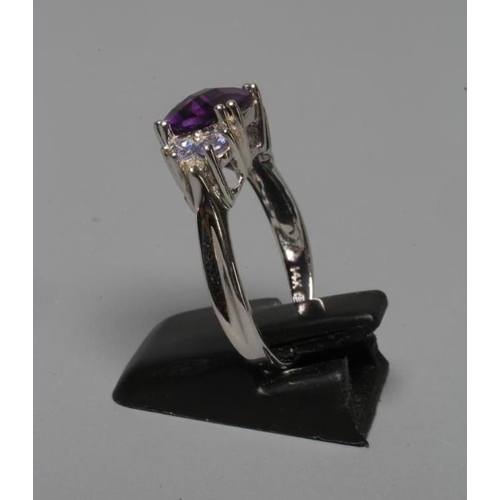 225 - AN AMETHYST RING, the rose cut cushion stone claw set between shoulders each point set with two tanz... 