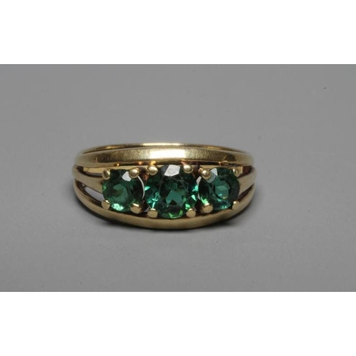 235 - A THREE STONE GREEN TOURMALINE RING, the circular facet cut stones claw set to open shoulders and a ... 