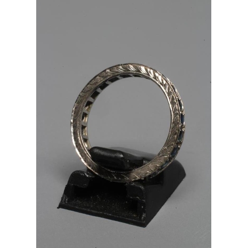 248 - A SAPPHIRE ETERNITY RING, the numerous small circular facet cut stones point set to a leaf engraved ... 