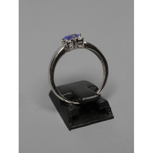 252 - A TANZANITE AND DIAMOND RING, the square facet cut tanzanite claw set with four small diamonds to ea... 