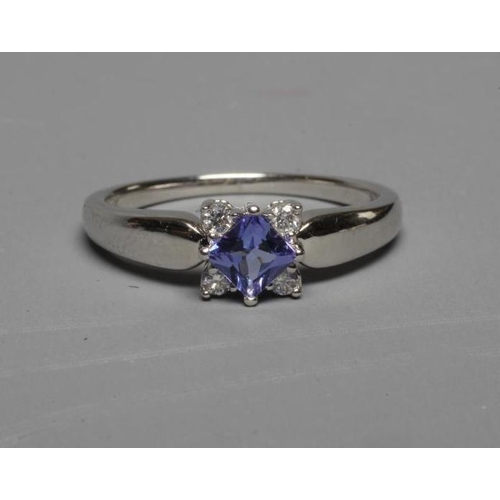 252 - A TANZANITE AND DIAMOND RING, the square facet cut tanzanite claw set with four small diamonds to ea... 