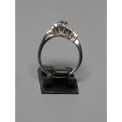 262 - A SAPPHIRE AND DIAMOND ABSTRACT CLUSTER RING, the circular facet cut sapphire claw set to a semi-who... 