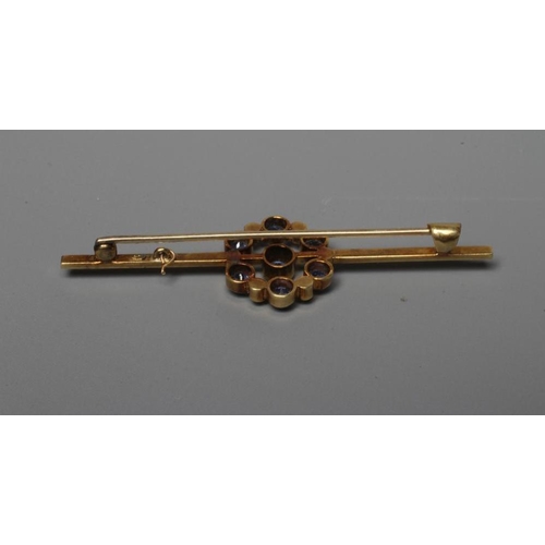 279 - AN EDWARDIAN BAR BROOCH centred by a circular facet cut sapphire within an open border of six collet... 