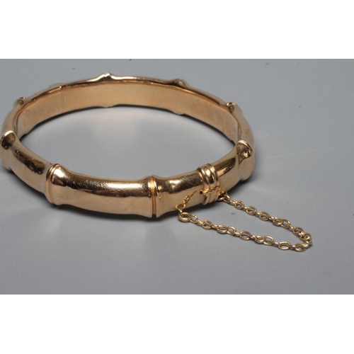 281 - A LATE VICTORIAN FAUX BAMBOO STIFF HINGED BANGLE, unmarked, with safety chain (Est. plus 24% premium... 