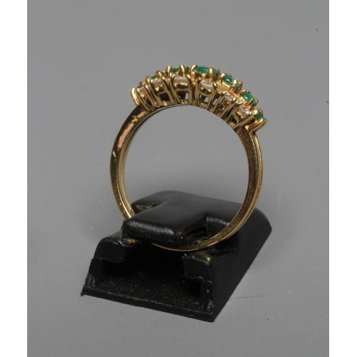 298 - AN EMERALD AND DIAMOND RING, the seven graduated circular facet cut emeralds within open borders of ... 