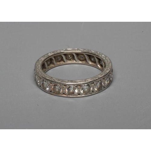 305 - A DIAMOND ETERNITY RING, the numerous brilliant cut stones pave set to an unmarked engraved white sh... 