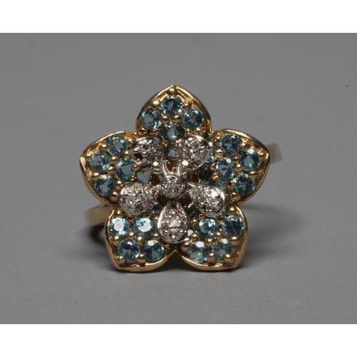 313 - A MODERN FLOWERHEAD CLUSTER RING point set with small mix cut diamonds to the centre within blue zir... 