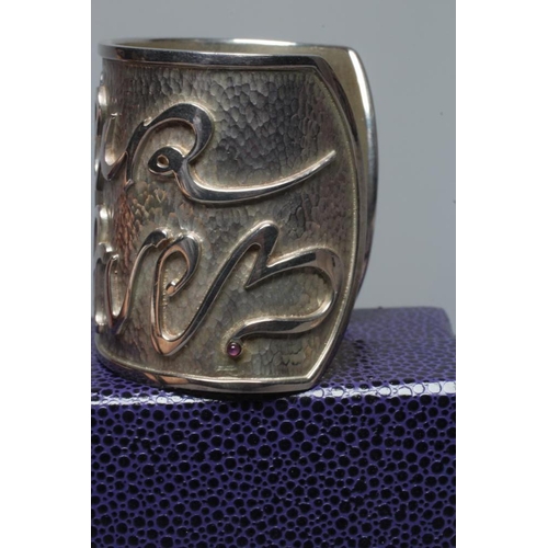 315 - A MODERN WIDE SILVER CUFF by Hamilton & Inches, Edinburgh 2002, cast in low relief with 'Mon Coeur A... 