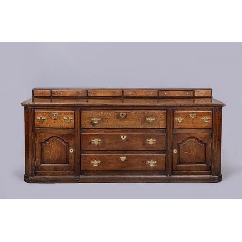 834 - A GEORGIAN OAK ENCLOSED DRESSER, late 18th century, the moulded edged plank top with raised back con... 