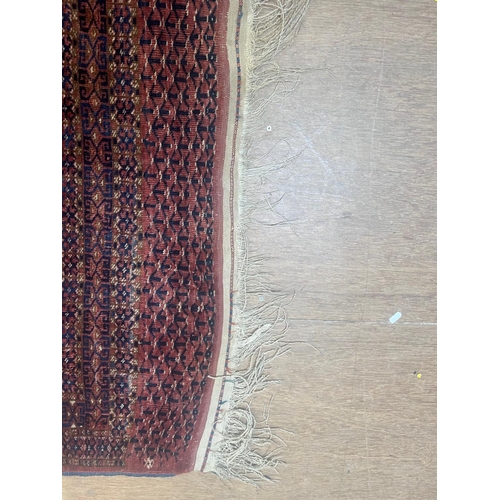 544 - A TEKKE DESIGN RUG, the madder field with a repeating pattern of three rows of quartered Guls within... 