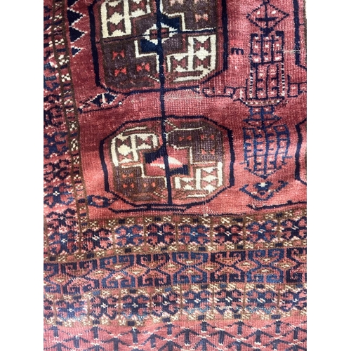 544 - A TEKKE DESIGN RUG, the madder field with a repeating pattern of three rows of quartered Guls within... 