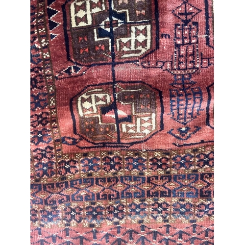544 - A TEKKE DESIGN RUG, the madder field with a repeating pattern of three rows of quartered Guls within... 