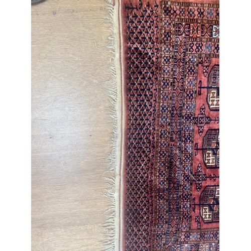 544 - A TEKKE DESIGN RUG, the madder field with a repeating pattern of three rows of quartered Guls within... 