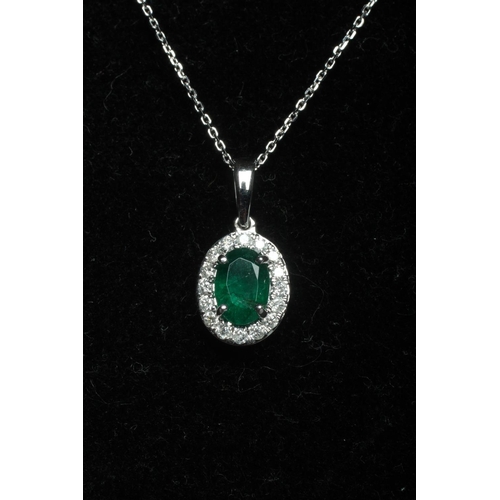 276 - AN EMERALD AND DIAMOND PENDANT, the oval facet cut emerald claw set to a border of small round brill... 
