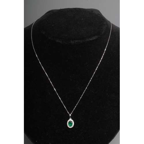 276 - AN EMERALD AND DIAMOND PENDANT, the oval facet cut emerald claw set to a border of small round brill... 