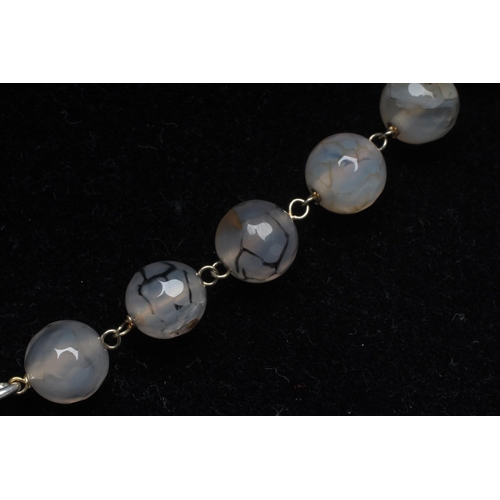 283 - A STRING OF FACET CUT MOSS AGATE BEADS, the pave set diamond lobster clasp with a cream enamel amd d... 