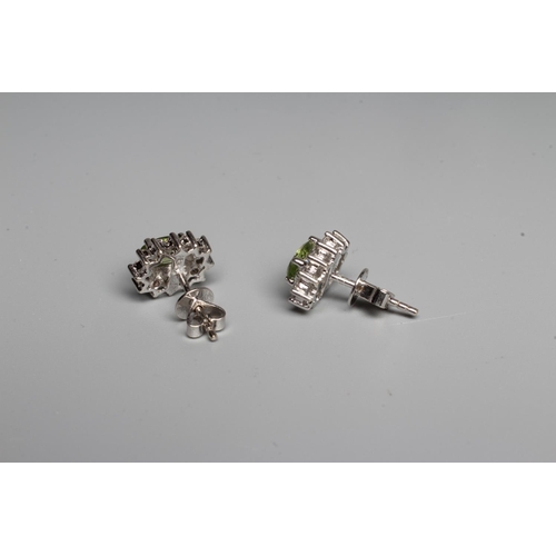 292 - A PAIR OF PERIDOT AND DIAMOND EAR STUDS, the oval facet cut peridots set to a border of twelve point... 