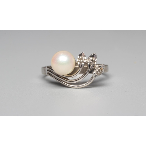 294 - A DRESS RING, peg set with a cultured pearl beside three leaves each pave set with a small diamond t... 