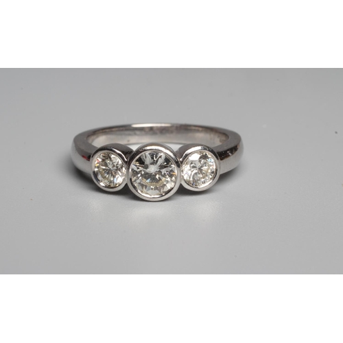 299 - A THREE STONE DIAMOND RING, the central round brilliant cut stone open back collet set and flanked b... 