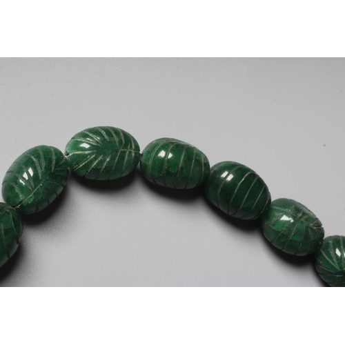 302 - A STRING OF GRADUATED CARVED OVAL GREEN ONYX BEADS with silver clasp