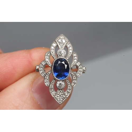 319 - AN EDWARDIAN STYLE SAPPHIRE AND DIAMOND DRESS RING, the central oval facet cut sapphire open back co... 