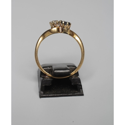 326 - A TWO STONE SAPPHIRE AND DIAMOND CROSSOVER RING, both stones claw set to a plain shank, indistinctly... 