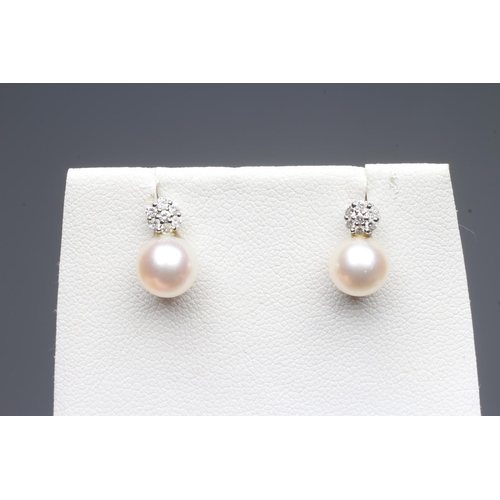 330 - A PAIR OF PEARL AND DIAMOND EAR STUDS, the peg set cultured pearl below a small seven stone diamond ... 