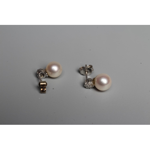 330 - A PAIR OF PEARL AND DIAMOND EAR STUDS, the peg set cultured pearl below a small seven stone diamond ... 