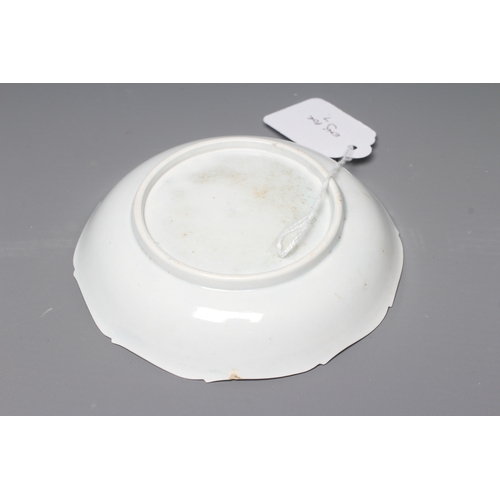 36 - AN ENGLISH PORCELAIN SAUCER, c.1755, of dished circular form with barbed rim, painted in underglaze ... 