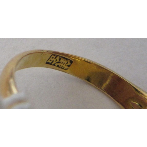 343 - A CHINESE RING, the oval cabochon polished jade panel claw set to stepped shoulders and a plain gold... 