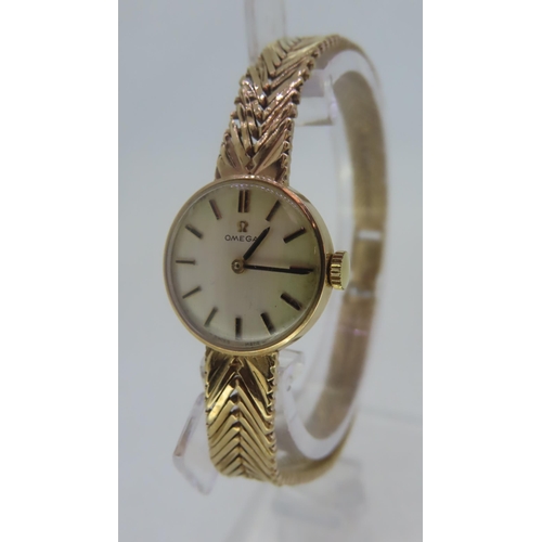 211 - A Ladies' Omega 9 ct. gold wind up wrist watch with integral strap - total weight including movement... 