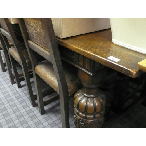 82 - Large oak dining table with heavily carved pillar to each corner and six studded leather chairs