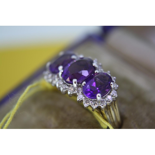 136 - Three stone amethyst and diamond ring set in gold - size O