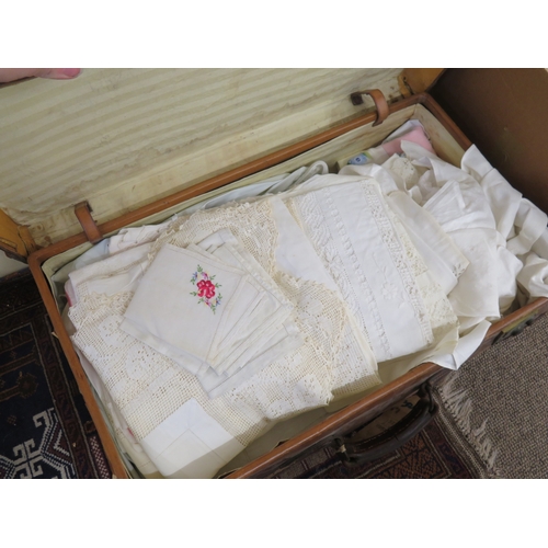 180 - A good brown leather suitcase with brass fittings containing table linen