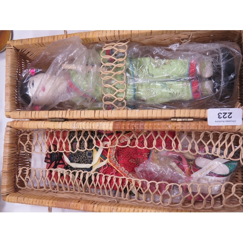 223 - A Chinese doll with outfits in a wicker basket