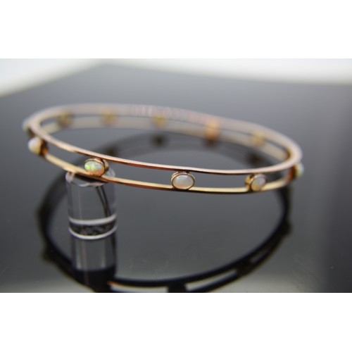 316 - 9ct gold bangle with oval opals to the surround, total weight 11.7 grams